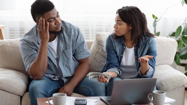 ouple accounting family budget at home, wife scolding her husband for overspending and lack of money