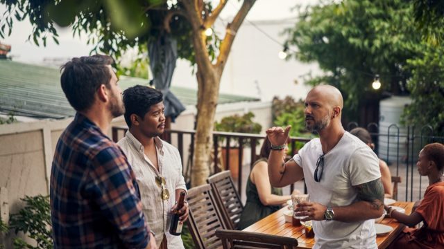 a small group of men talking outside at a party