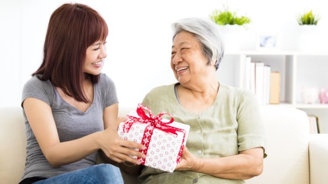 happy young woman giving present to grandmother