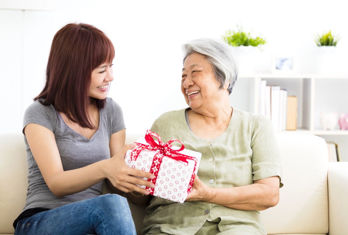 Glückliche junge Frau, die ihrer Großmutter ein Geschenk gibt