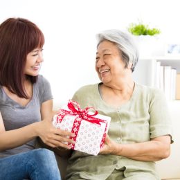 happy young woman giving present to grandmother