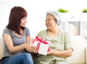 happy young woman giving present to grandmother