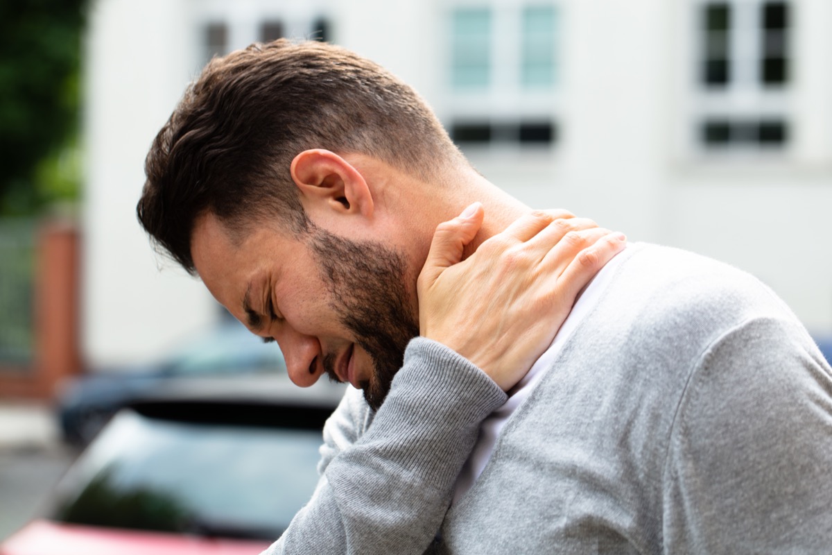 man touching his neck in pain