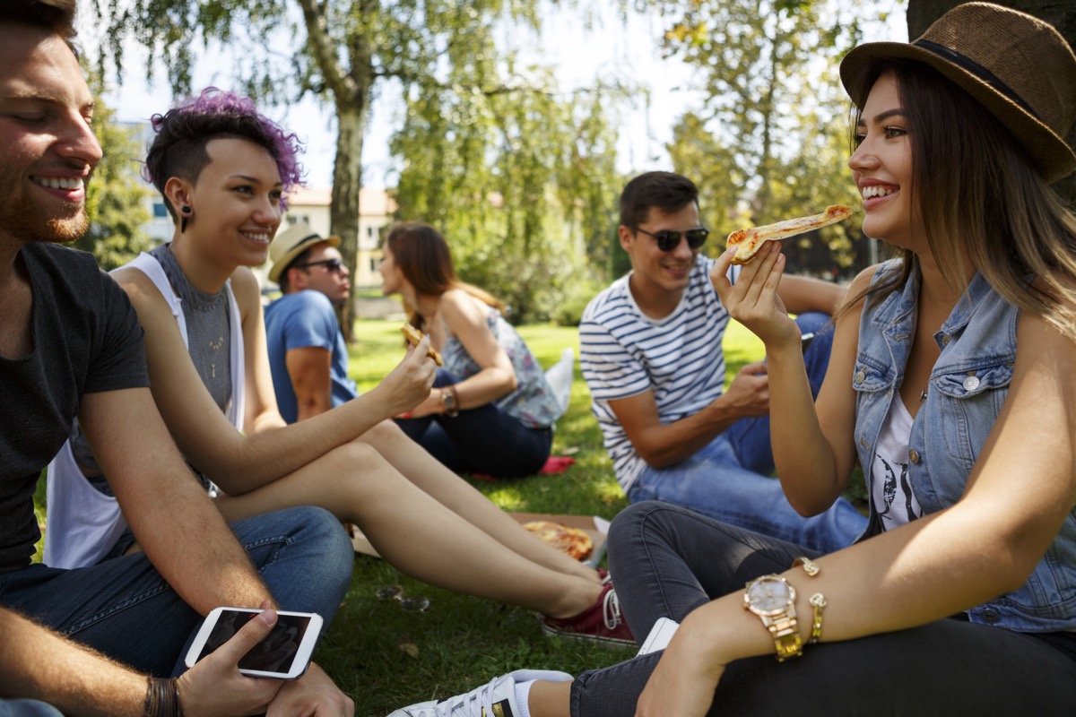 Oamenii se adună într-un parc, mănâncă pizza și nu există măști