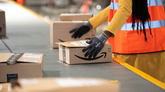 close up of amazon worker handling box at factory