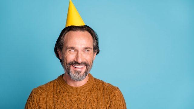 Middle aged man smiling with birthday hat on
