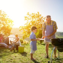 family barbecuing outside with tent in the background