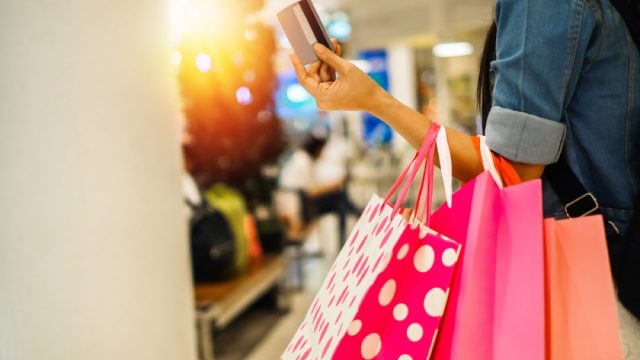 close up of woman holding credit card and carrying shopping bags