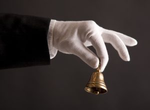 butler's hand in white glove holding a small bell