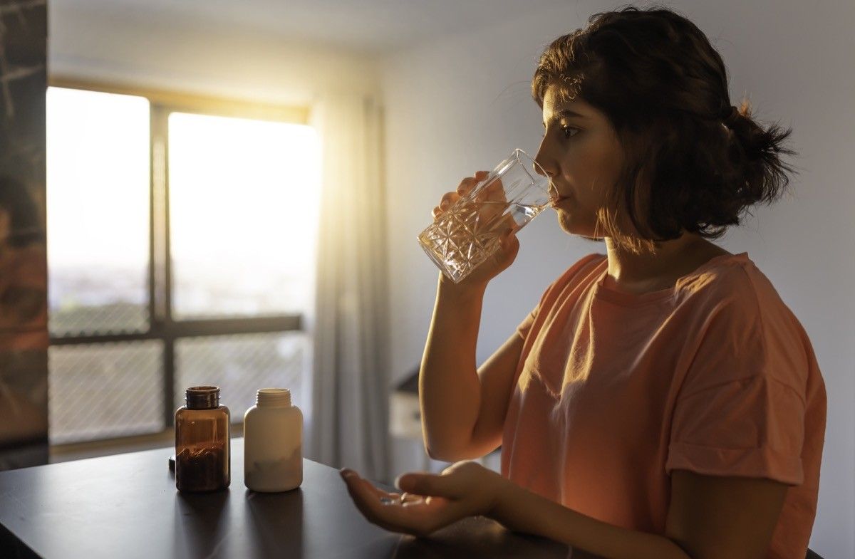 Shot of a young woman taking supplements at home