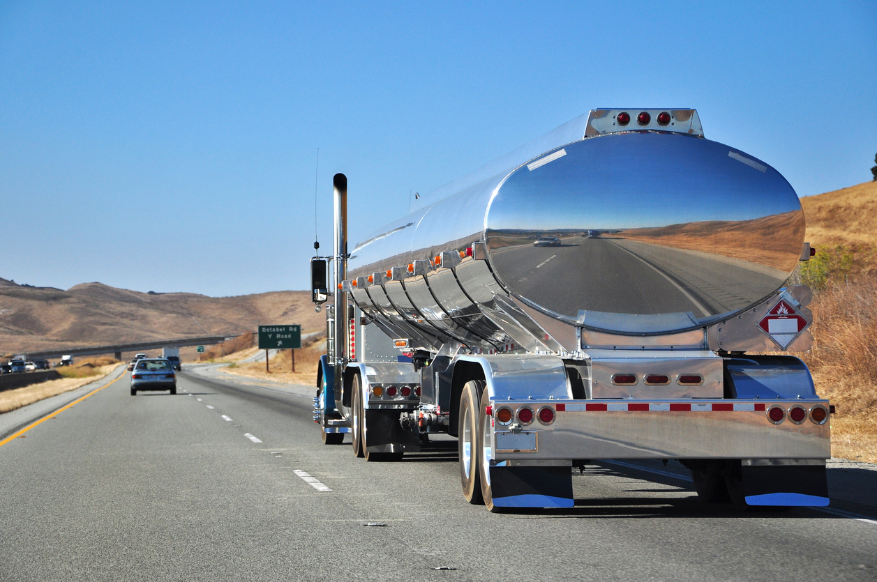 A chrome gas tanker truck driving down a highway