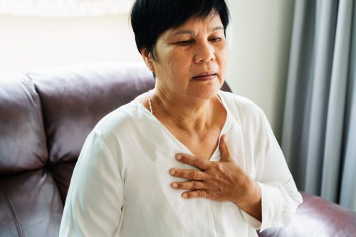 Eine alte Frau hat einen Herzinfarkt und fasst sich an die Brust