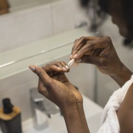 Unrecognizable woman looking at her nails, while removing her nail polish.