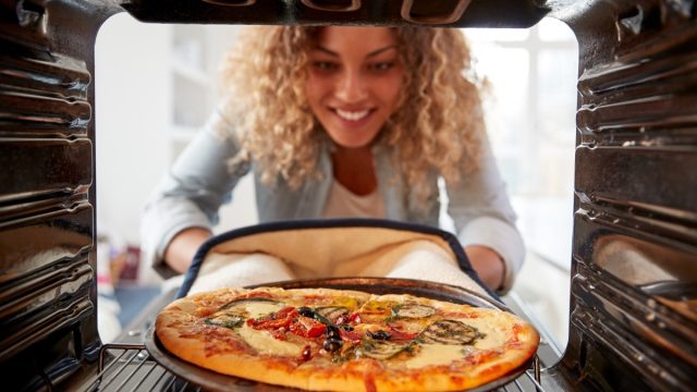 woman making pizza in home oven