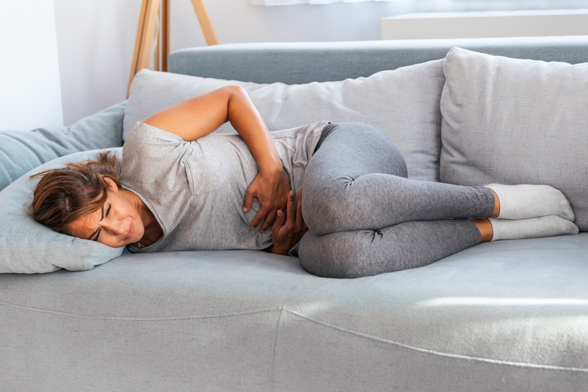 woman on couch looking uncomfortable with stomach pain