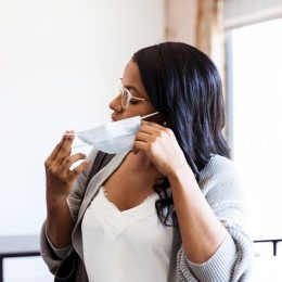 woman taking off or removing face mask indoors