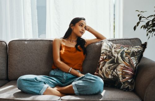 woman sitting on couch with hand on head
