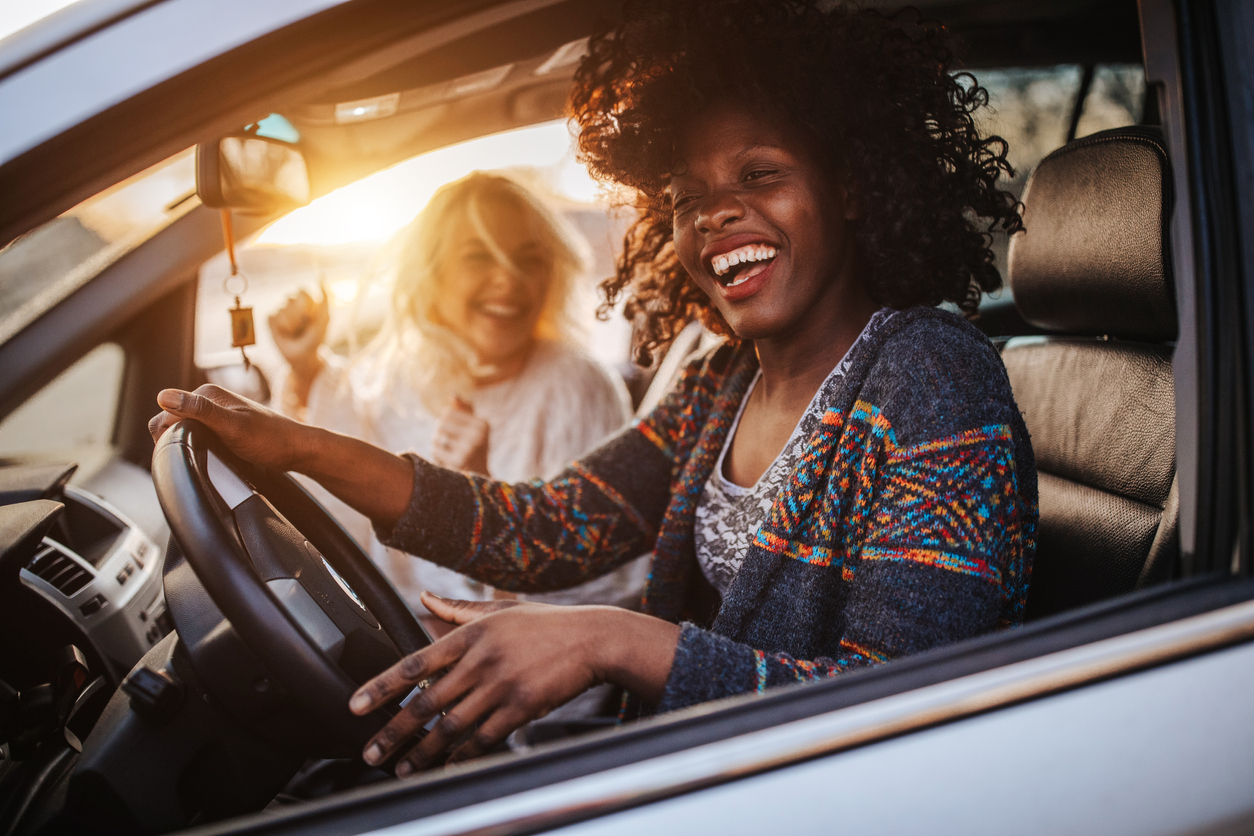 Two cheerful young women driving in a car