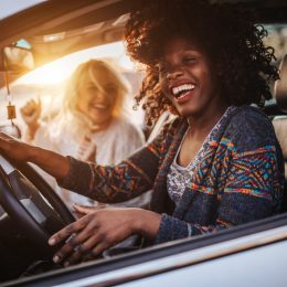 Two cheerful young women driving in a car