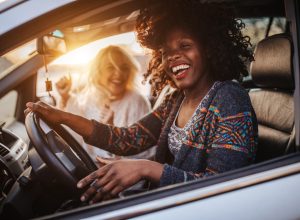 Two cheerful young women driving in a car