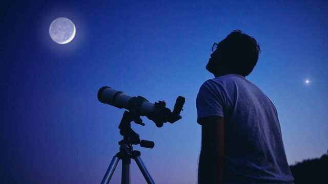 Man looking at moon with telescope