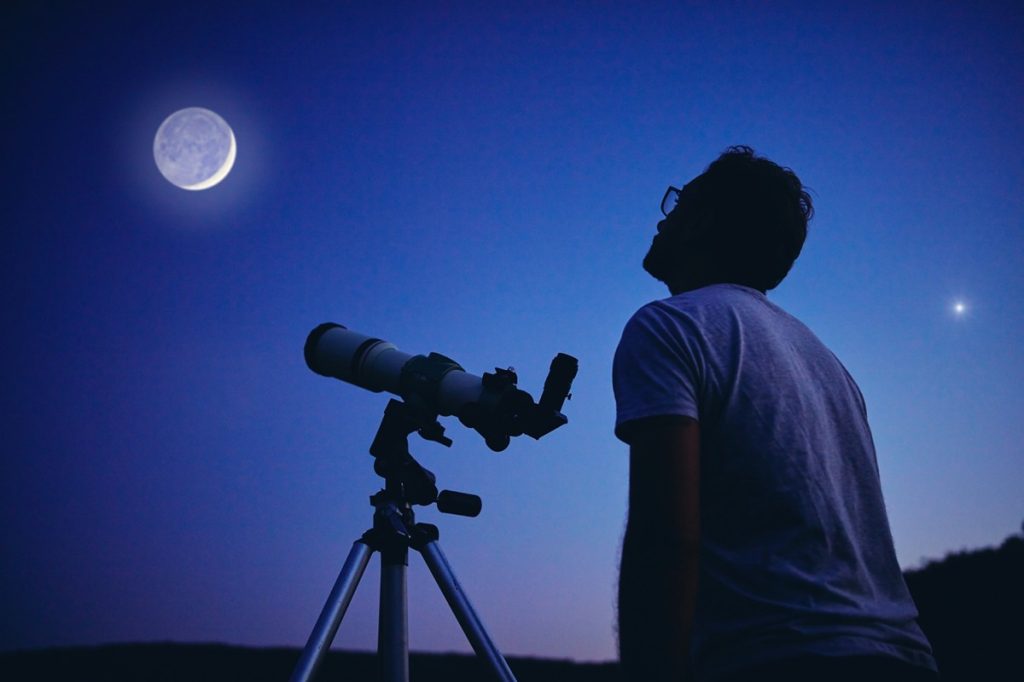 Người đàn ông nhìn mặt trăng bằng kính thiên văn