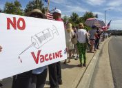 A protester holds an anti-vaccination sign saying "No vaccine"