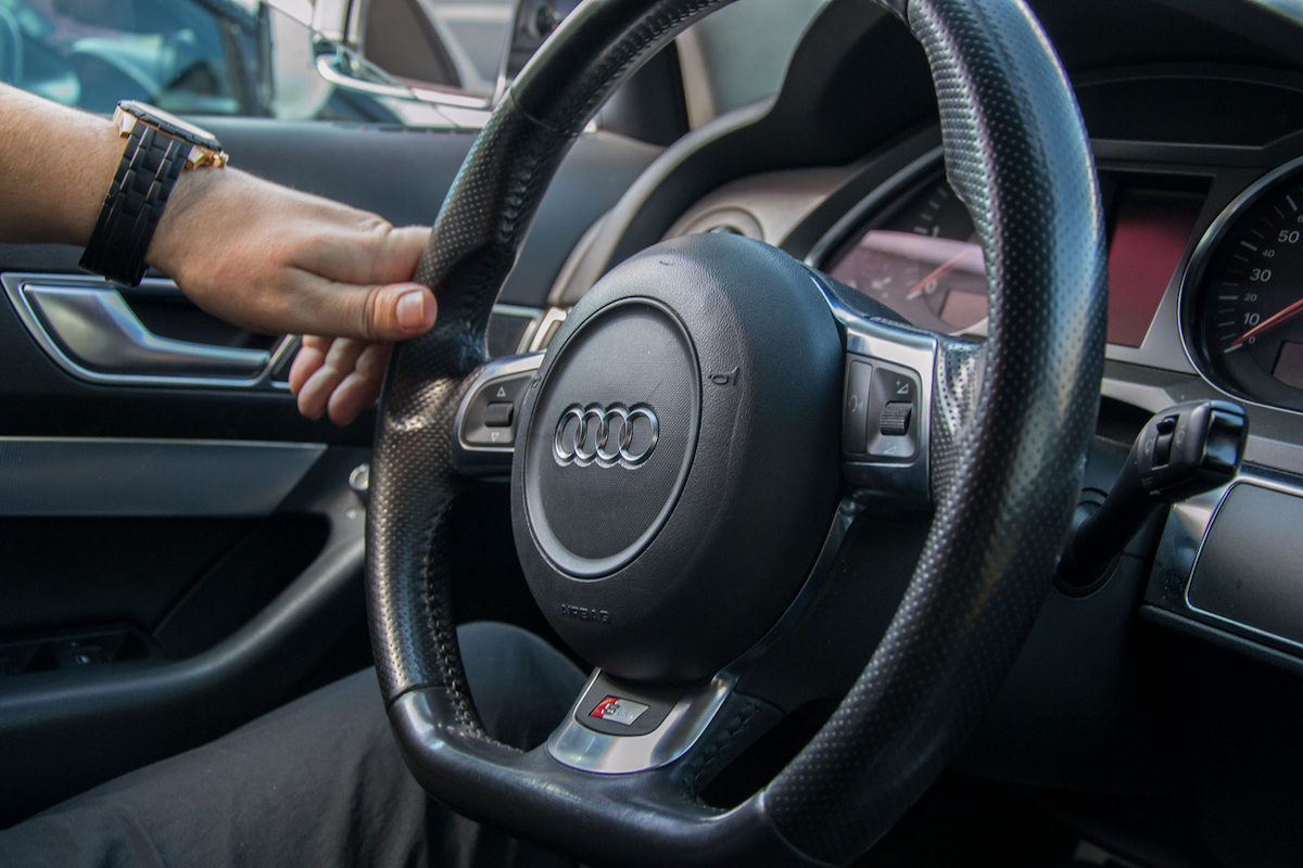 Man hands holds steering wheel of Audi