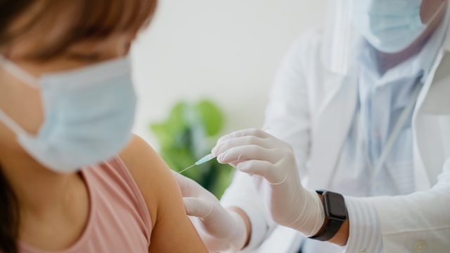 woman getting a vaccine injection on her arm from a healthcare worker