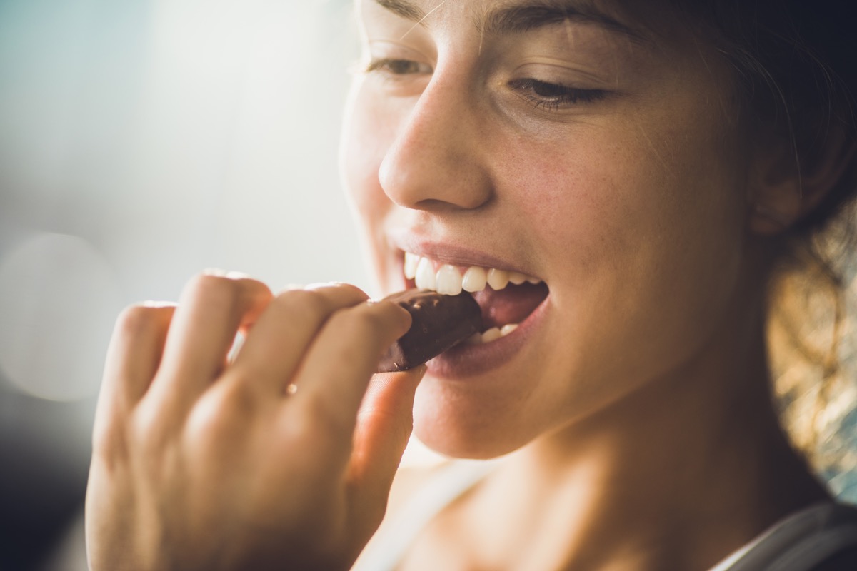 Close up of young beautiful woman biting chocolate candy.