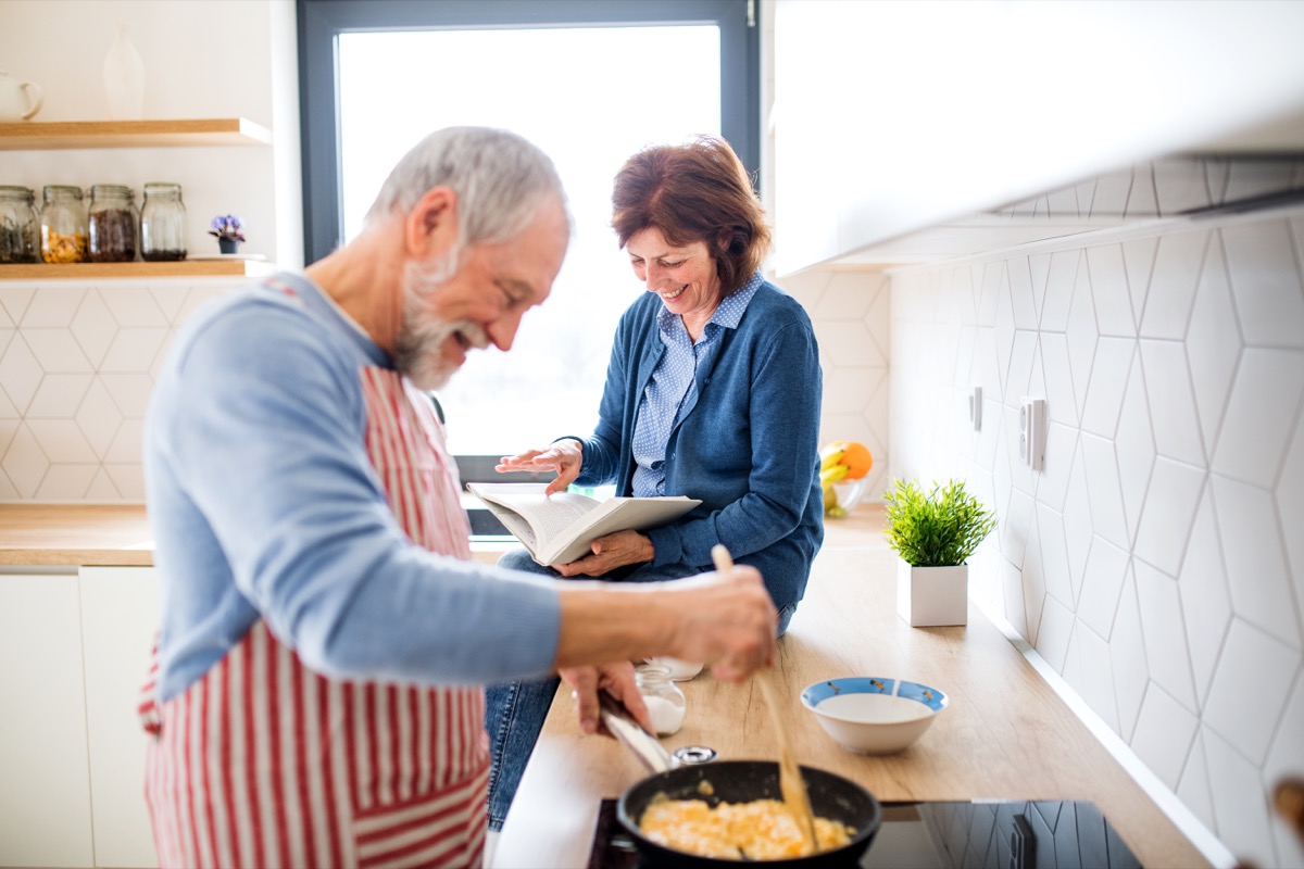 Portretul unui cuplu de bătrâni îndrăgostiți în casă, gătind.