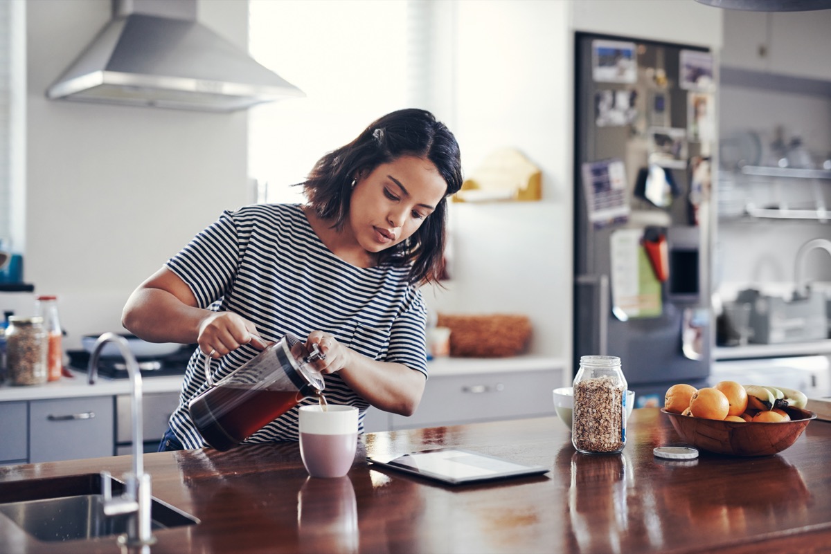 Shot of an attractive young woman drinking coffee while using a digital tablet at home