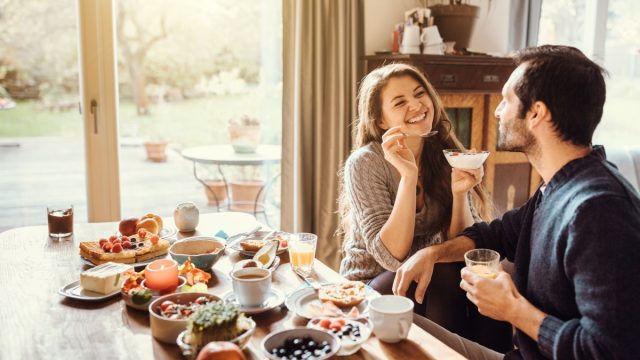 young couple sitting on a table and having breakfast together