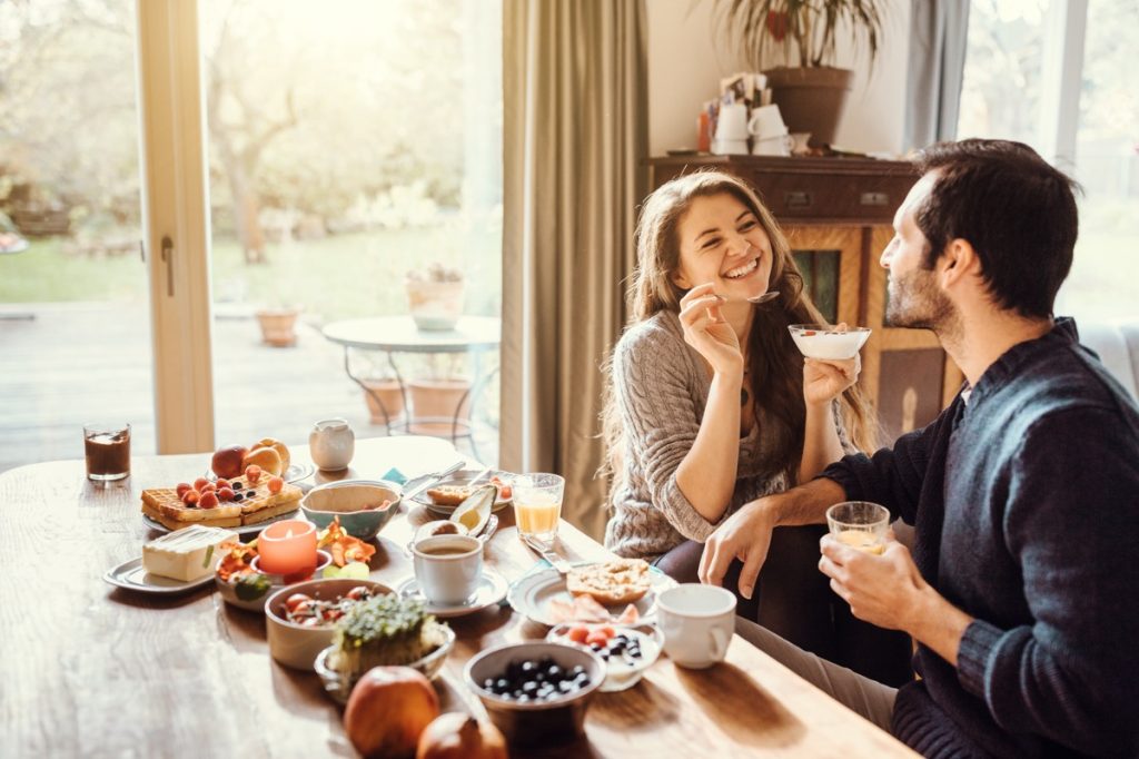 young man and woman sitting on a table and having breakfast together