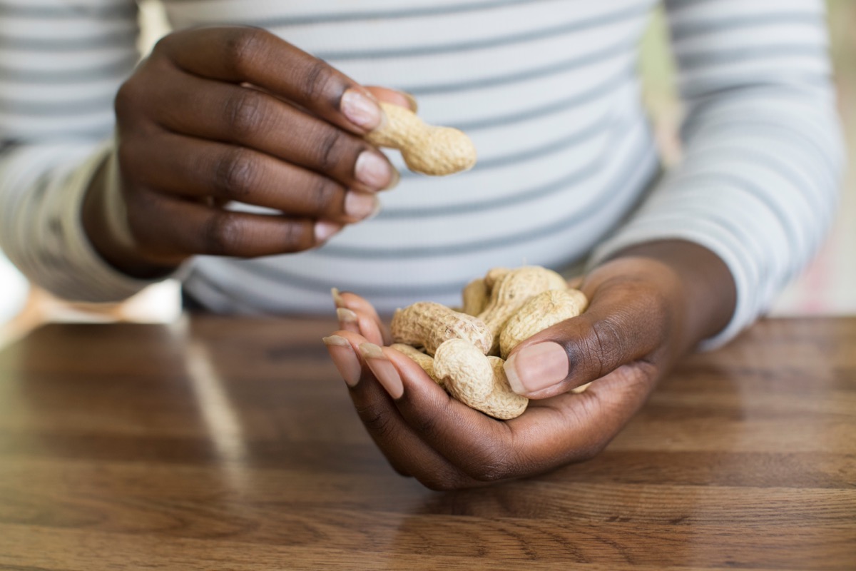 Close Up Of Teenage Girl With Handful Of Peanuts In Shells