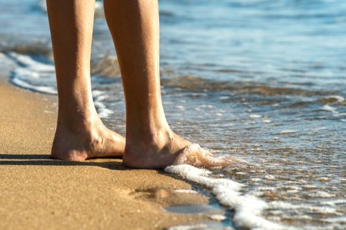 Die Füße der Frau im Meerwasser