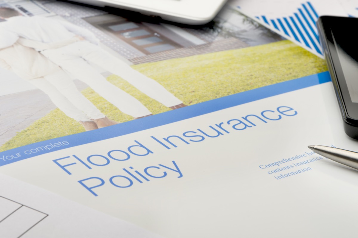 Flood insurance policy brochure with image of a couple in front of a house. Cover of a brochure with technology. Mobile phone, digital tablet. Image on brochure is fully released and can be found in my portfolio. Image number 26822047