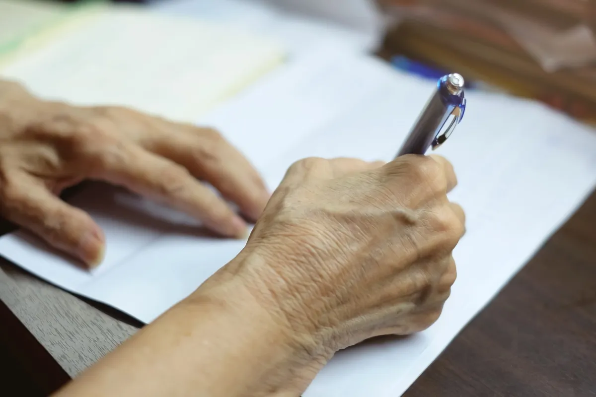 Older person writing on paper