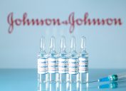 A se of 5 vials of Johnson & Johnson COVID-19 vaccine in front of the company's logo