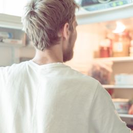 young man searching for food in fridge at home