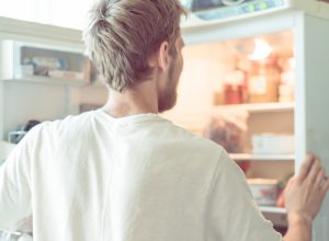 young man searching for food in fridge at home