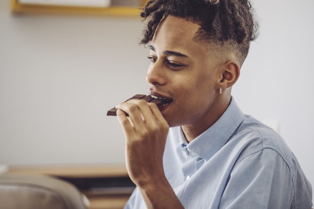 young man biting into chocolate