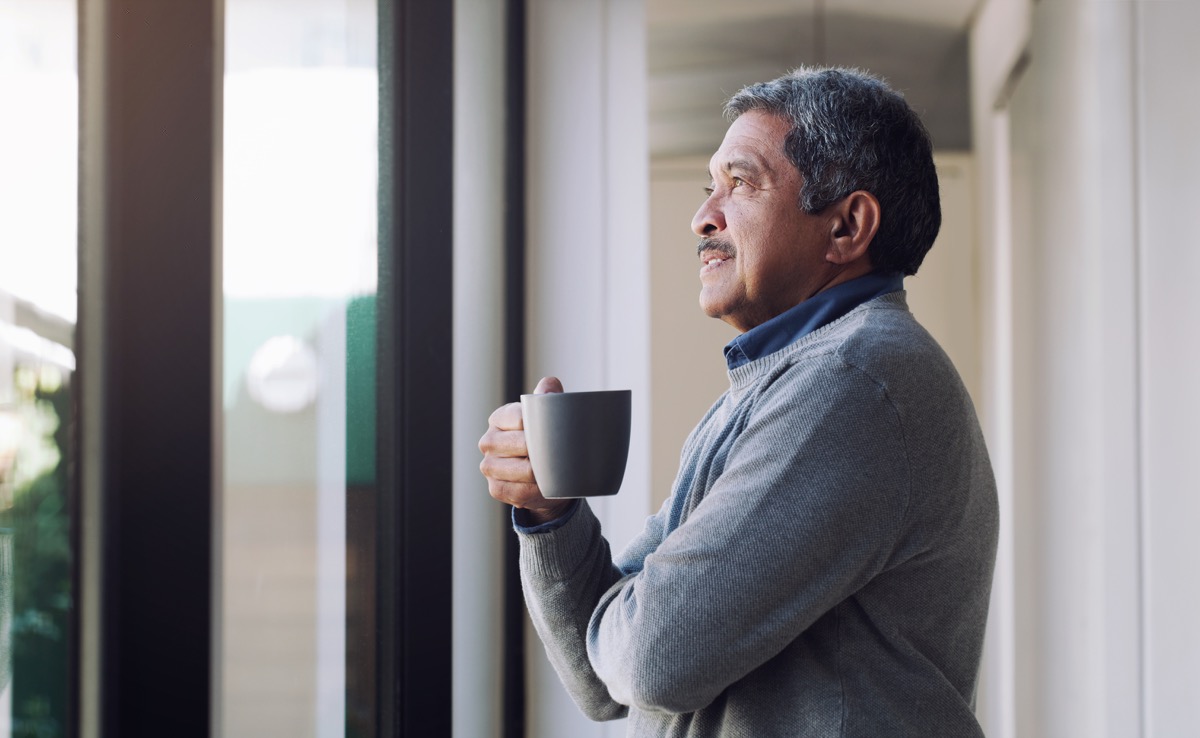 man drinking coffee and looking thoughtfully out of a window