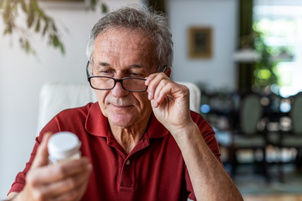 man using glasses to read supplement label