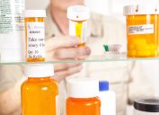 Senior adult man gets prescription medicines out of his medicine cabinet. Close up of hands and pills.