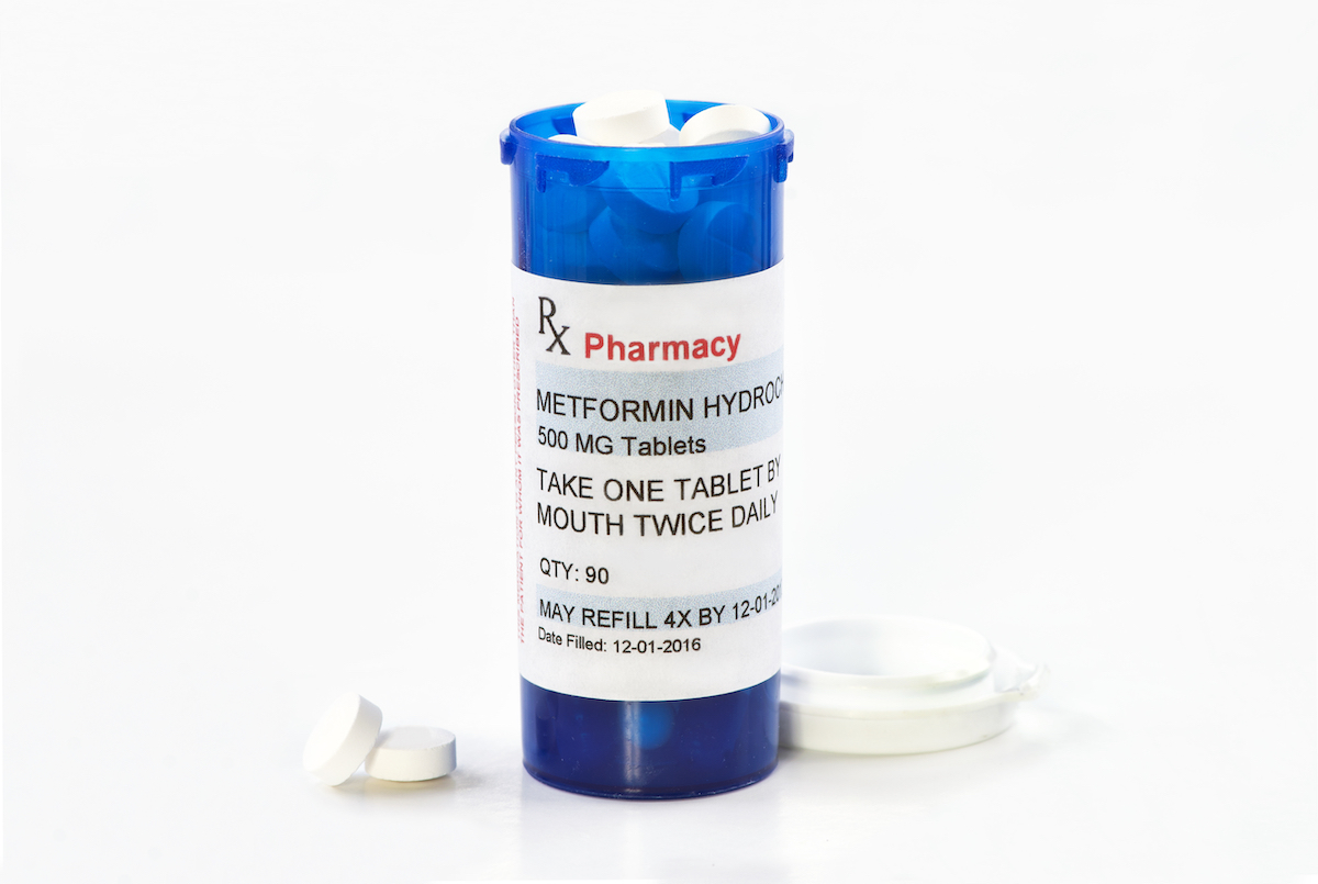 Metformin prescription bottle with tablets and lid.