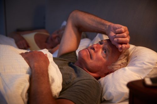 older man with gray hair awake in bed at night