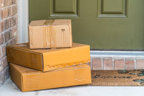 Paketzustellung, Kisten vor der Haustür des Vorgartens Kisten des Hauses zur Zustellung.  3 Kisten stehen vor der Haustür.  Nahaufnahme der Boxen