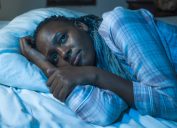 woman lying on bed at home unhappy and sleepless at night feeling overwhelmed suffering depression problem and insomnia