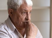A senior man sitting with a concerned look on his face, potentially suffering from dementia